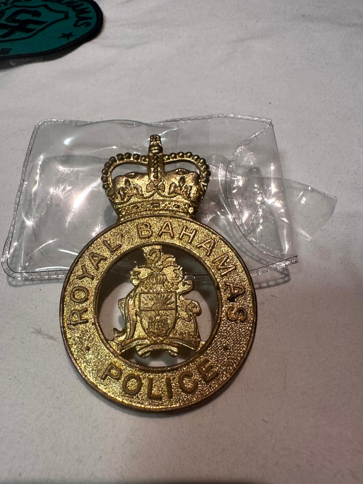 Royal Bahamas Police gold metal cap badge in protective sleeve