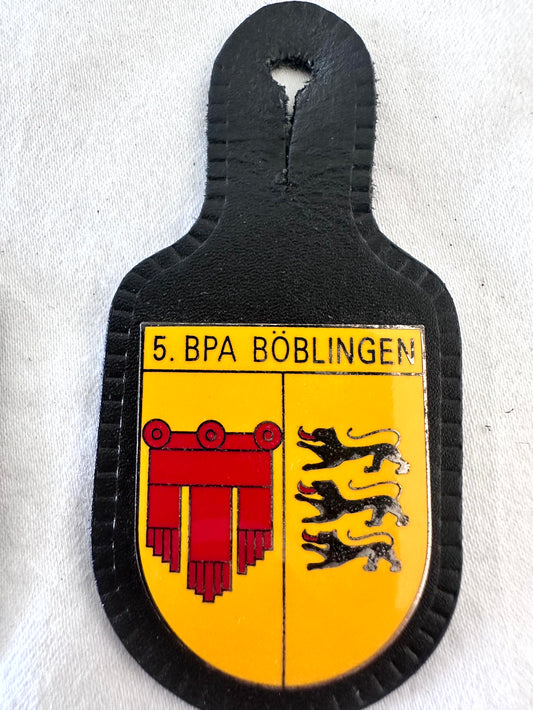 5. BPA Böblingen Bereitschaftspolizeiabteilung Baden-Württemberg riot police battalion black leather pocket badge, gold yellow shield field with black 5. BPA BÖBLINGEN header, left gold field with large red Ionic Corinthian column capital with volute scrolls and red draped curtain Pallium hanging bands Böblingen city arms, right gold field with two black passant Württemberg lions