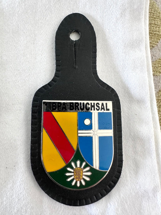 1. BPA Bruchsal Bereitschaftspolizeiabteilung Baden-Württemberg riot police battalion black leather pocket badge, three-part shield with white 1.BPA BRUCHSAL header, left Baden red diagonal on gold, right blue quartered field with white cross and white roundel, lower green field with white daisy edelweiss and gold centre